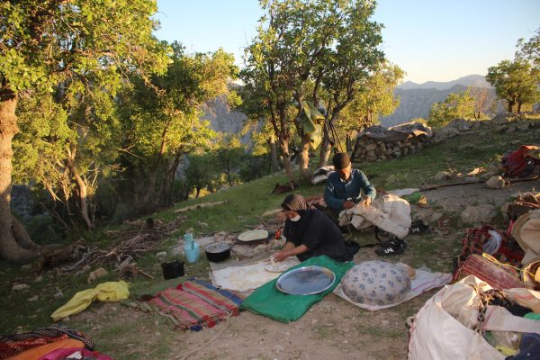 Stopping for the night lunch during the spring migration with Shah Goli and Ali Ghoabad’s family in 2023. Shah Goli is making bread and Ali Qhobad was fixing the bag for the donkeys. Shah Goli is wearing a mask against an insect that flies to the mouth and nose. Photo by Sacha Mouzin.